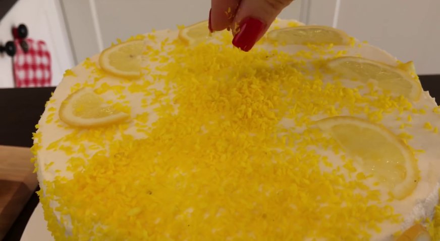 Лимонный торт: Украшаем торт лимонными дольками, оставшейся цедрой и подкрашенной в жёлтый цвет кокосовой стружкой.