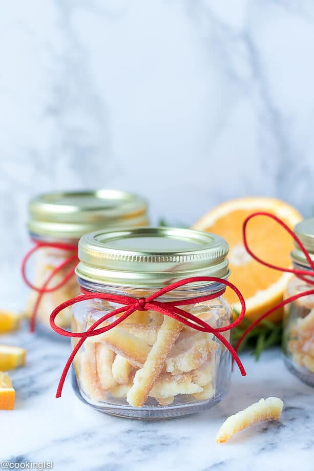 Small gift jars filled with candied orange peel slices, rolled into sugar. Easy candied orange peel recipe.