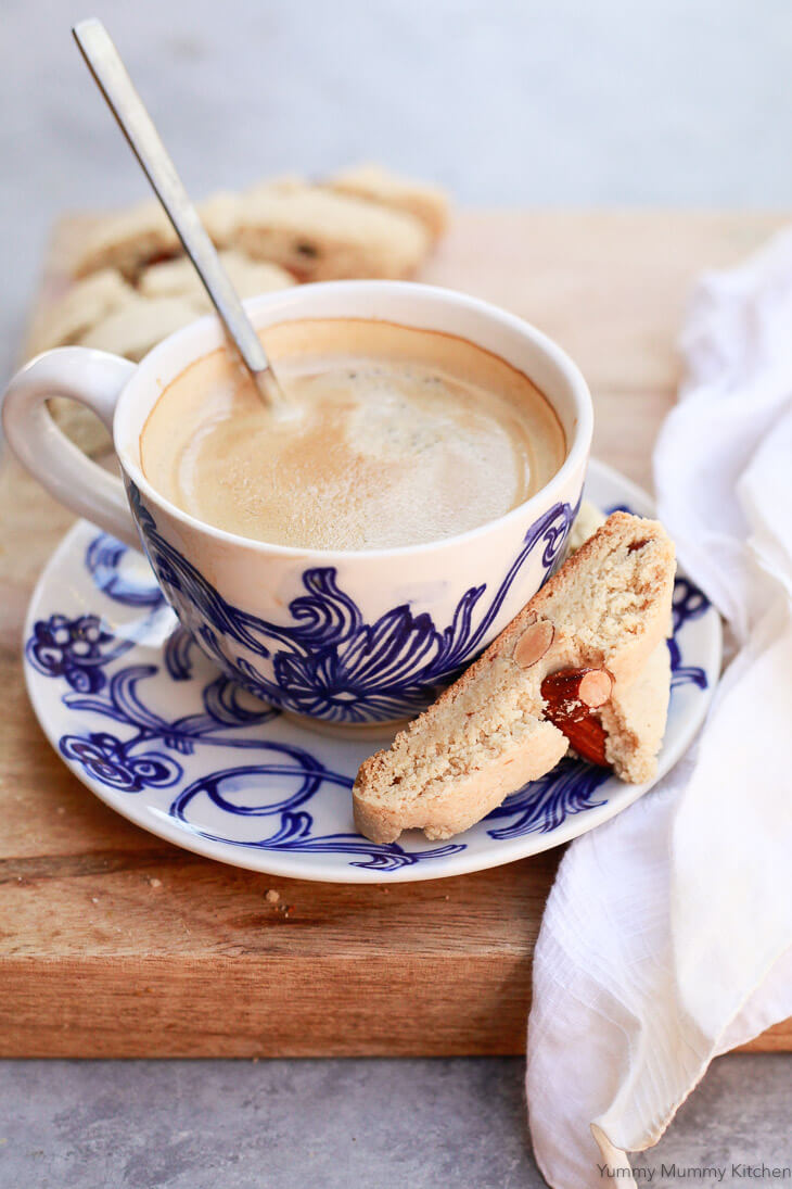 Gluten free almond cantucci biscotti on a plate with a cup of coffee. 
