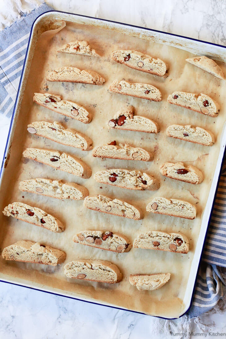 Sliced gluten free almond biscotti on a cookie sheet before the second baking. 