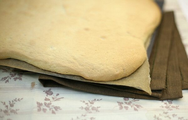 Пласт готового бисквита на противне с пекарской бумагой