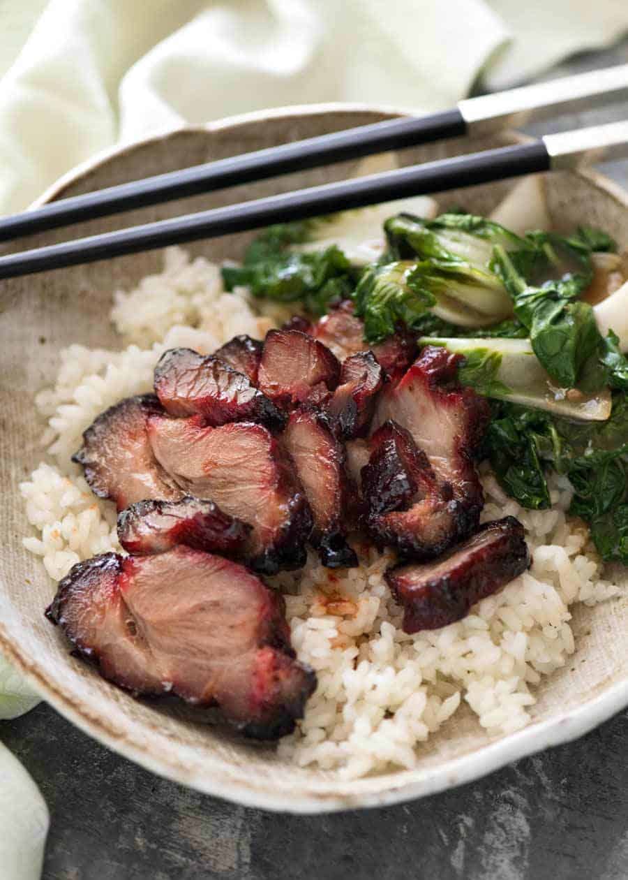 Char Siu (Chinese Barbecue Pork) served on rice with a side of steamed Chinese greens.