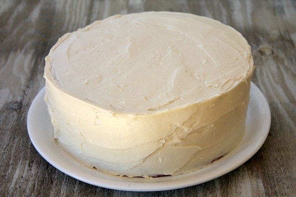 white frosting on a red velvet cake on a white plate