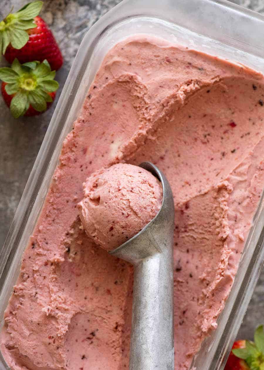 Creamy No Churn Strawberry Ice Cream in a glass dish being scooped with an ice cream scooper