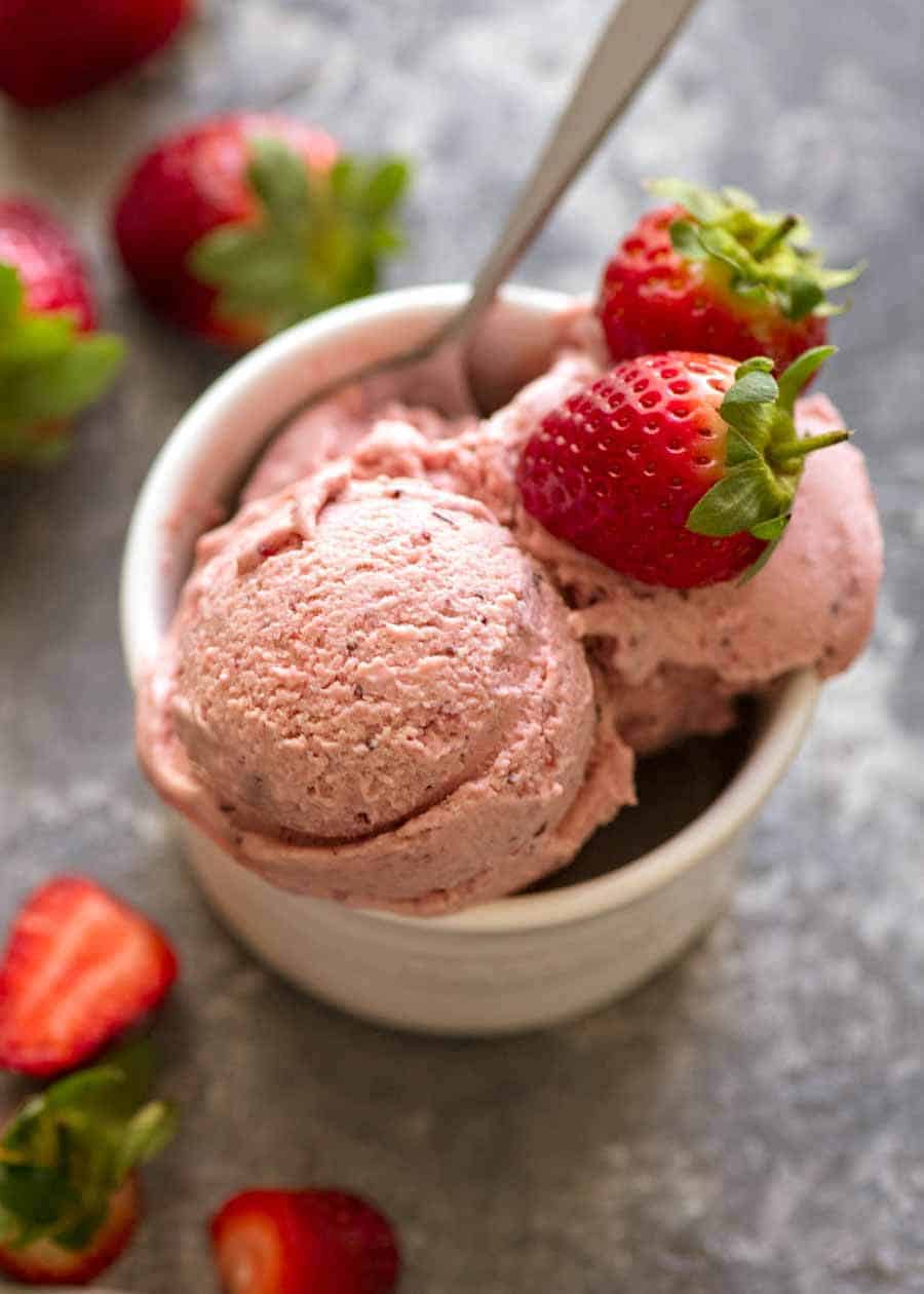 Creamy No Churn Strawberry Ice Cream in a small white dish topped with fresh strawberries, ready to be eaten